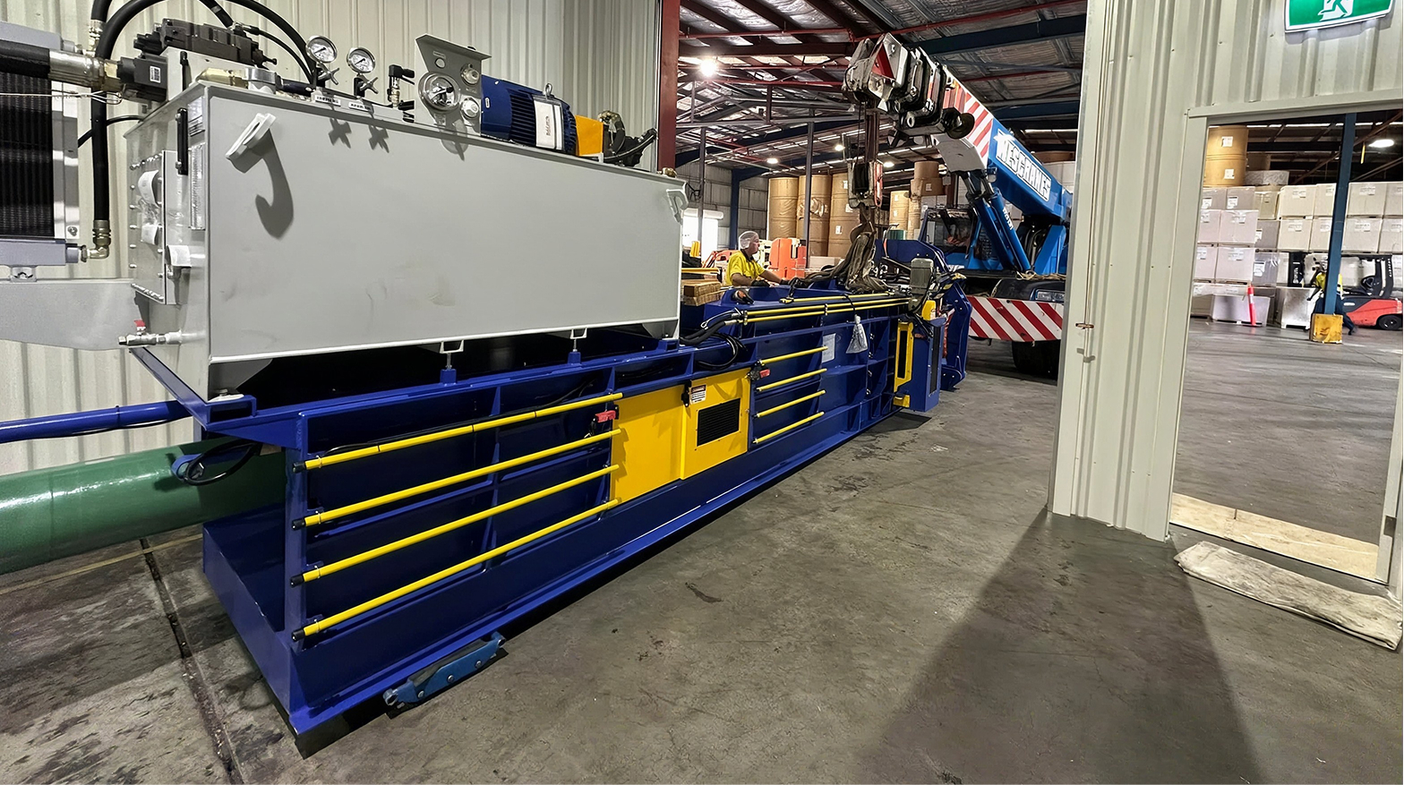 aWescranes mobile crane lowering heavy machinery inside a warehouse with staff nearby